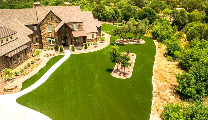 Aerial view of luxury stone home with artificial grass lawn