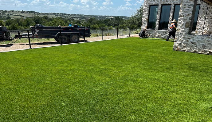 Workers installing an artificial turf lawn in a backyard.