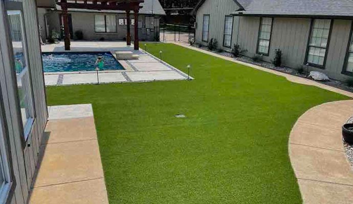 Backyard poolside turf installation with clean green lawn and modern outdoor living area between homes