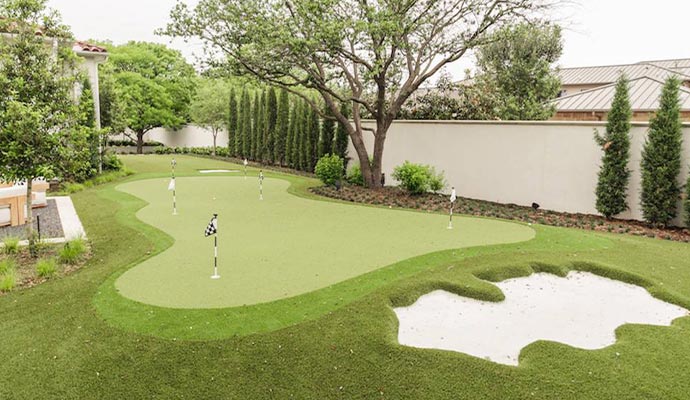 Backyard putting green with a sand trap and multiple holes.