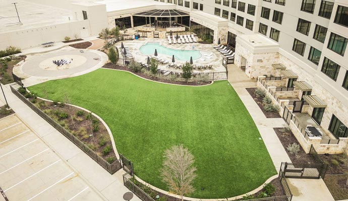 Commercial hotel courtyard with synthetic turf lawn and pool
