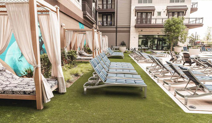 Commercial pool deck with artificial turf lounging area and cabanas