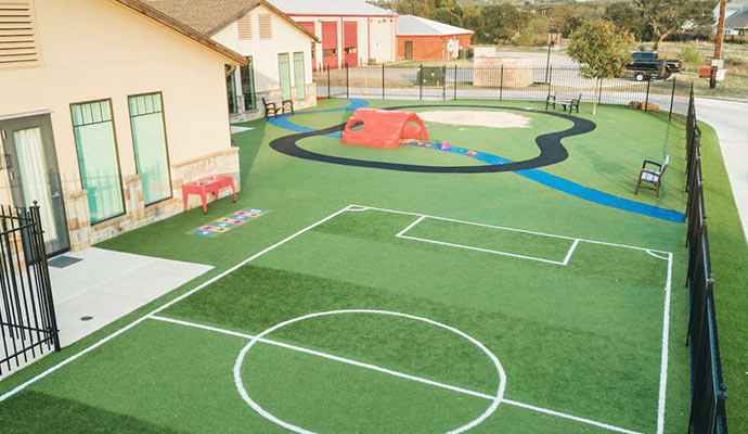 Modern daycare playground with artificial turf and a mini soccer field.