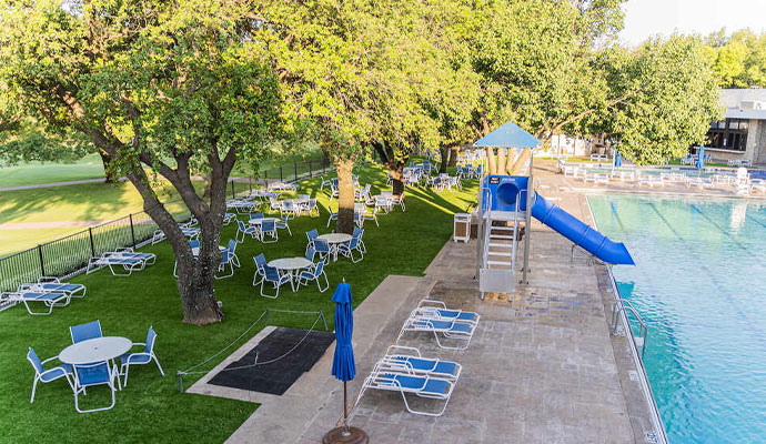 Poolside artificial grass lounge area with trees and seating