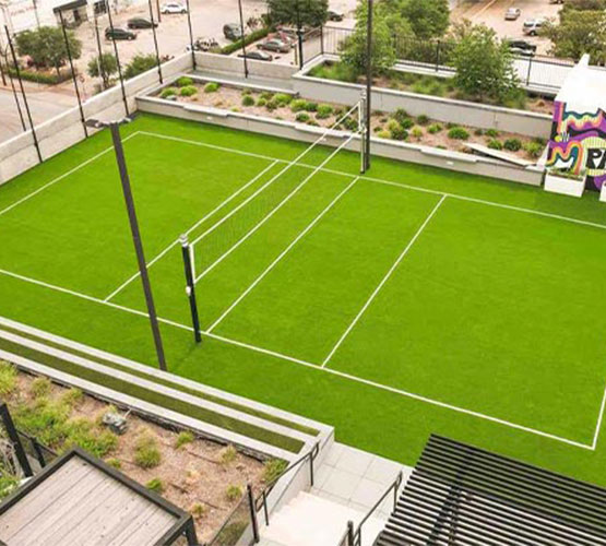 Rooftop volleyball court with artificial turf at a modern building.