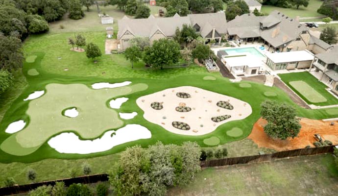 Aerial view of a completed residential landscape featuring putting greens, sand bunkers, and lawn areas.