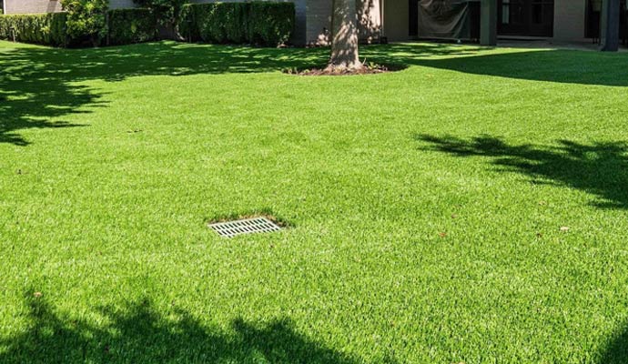 Outdoor drain cover set in green artificial turf backyard