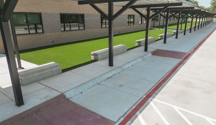 Installation of durable synthetic grass in a low-maintenance school grounds walkway area