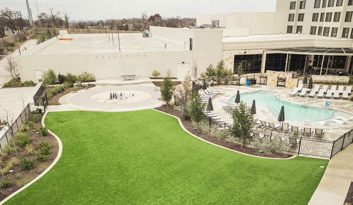Hotel courtyard with a pool and an artificial turf lawn.