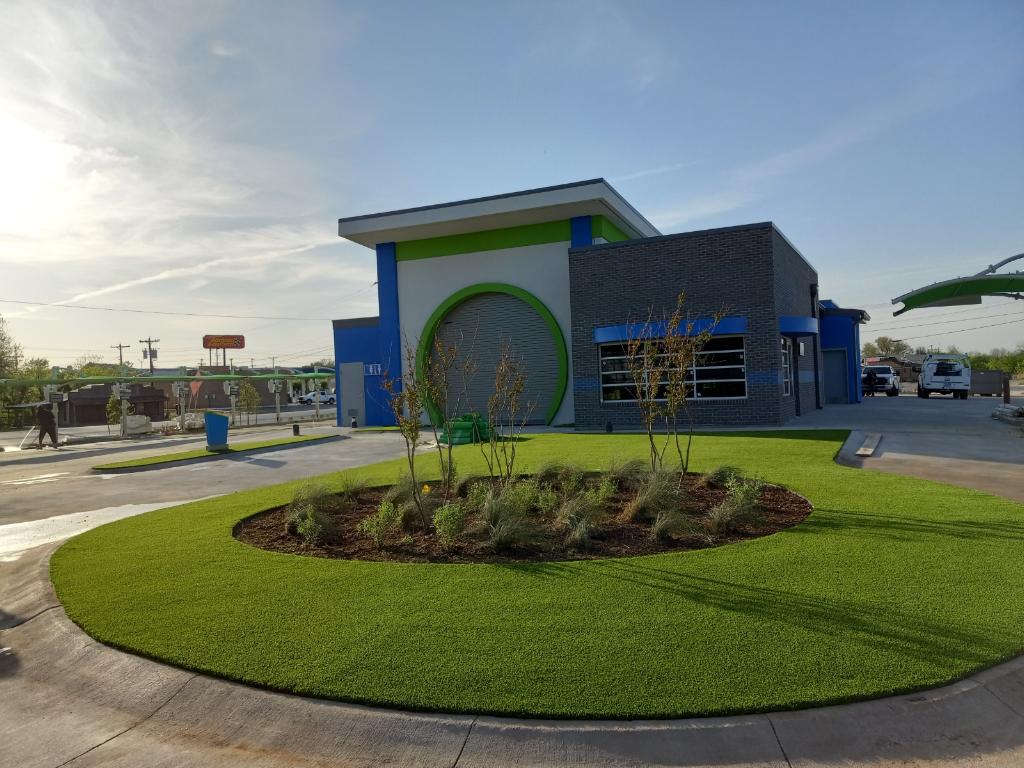Modern car wash exterior featuring new artificial turf landscaping, enhancing curb appeal and providing a year-round green, low-maintenance solution.
