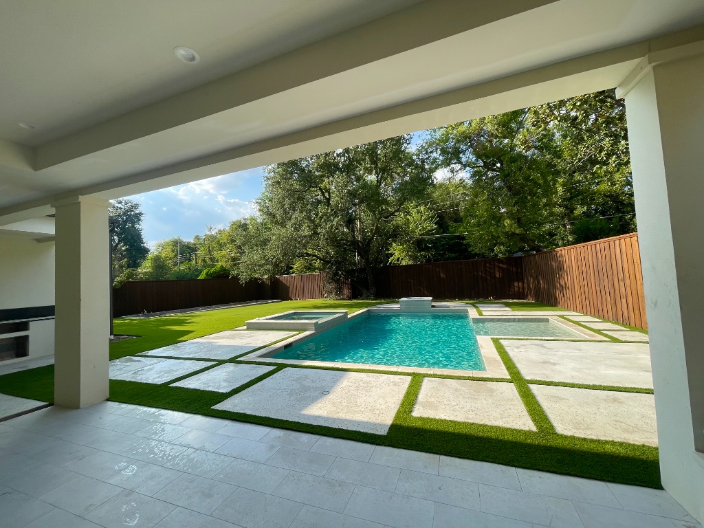 Stunning pool area backyard renovation featuring an innovative turf and paver design. The artificial grass pool decking uses synthetic turf strips for a clean, low-maintenance pool surround, creating a durable pool area and a functional outdoor space that is both safe and visually appealing