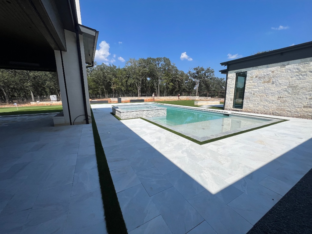 Modern artificial grass pool surround installation providing a clean, aesthetic border against white pool decking. This premium turf installation ensures a low-maintenance pool decking area, keeping the surface free from mud and debris, and creating a functional outdoor space that complements the home's contemporary design.
