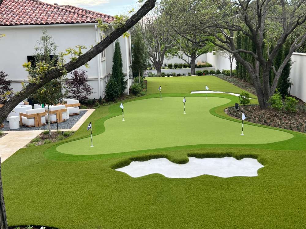 Residential backyard with putting green, sand bunkers, and outdoor seating.