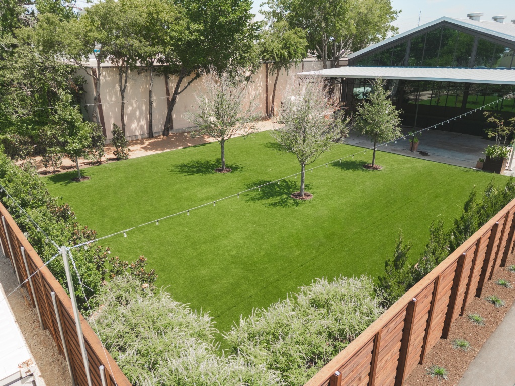 Pristine event venue synthetic grass area at Cullen Yards, perfect for weddings and special events. This commercial artificial turf installation, using Trek Turf, provides a year-round, low-maintenance wedding venue surface. The durable outdoor flooring remains green and elegant, aligning with the venue's upscale commercial design in Fort Worth.