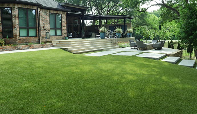 High-end backyard with an artificial turf lawn and a large patio.