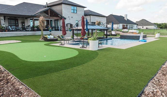Luxury backyard with a pool and an artificial turf putting green.