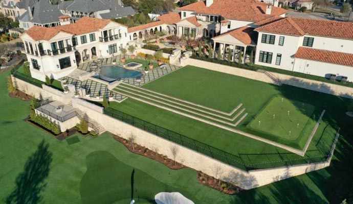 Aerial view of a mansion with a private artificial turf golf course.