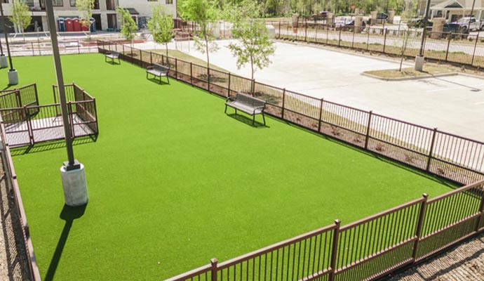 Fenced-in dog park with artificial turf and seating