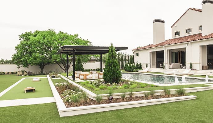 Professionally installed artificial turf installed in residential backyard in Cornhole Flowerbed Pool Pergola