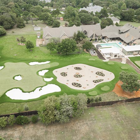 Aerial view of a completed residential landscape featuring putting greens, sand bunkers, and lawn areas.
