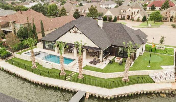 Bird's-eye view of a luxury backyard with a pool, artificial turf lawn, and putting green