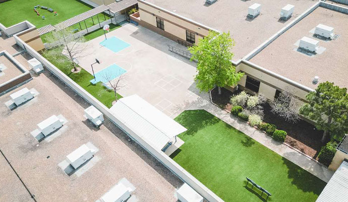 Aerial view of a school outdoor recreational courtyard with artificial turf and sports court