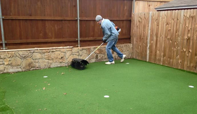 Worker removing debris from artificial grass